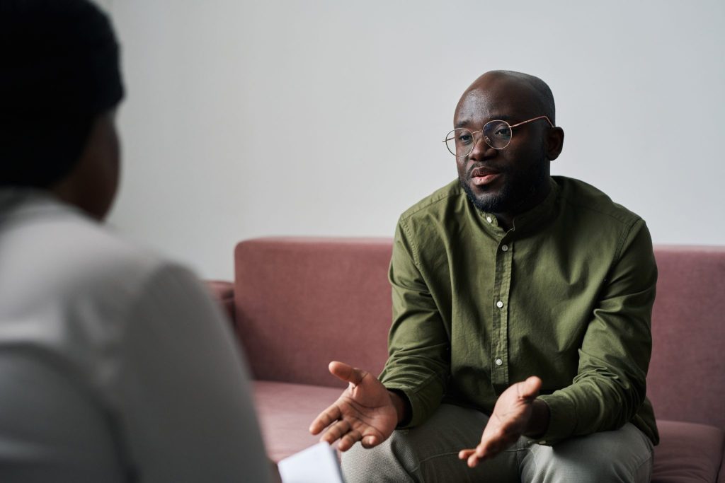 BIPOC counselling services. Young black man in casualwear sitting on couch during talk with a counsellor.
